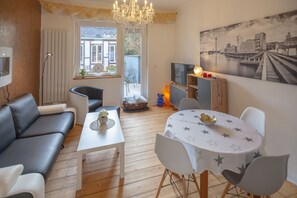 Relax in this stylish living room with a black leather sofa, round dining table, and cityscape painting.