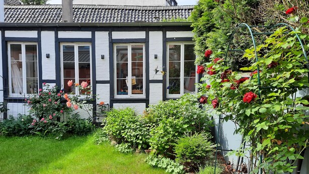 A traditional half-timbered house with a garden featuring roses and various shrubs. - Apartmenthaus Lorbach (Solingen)
