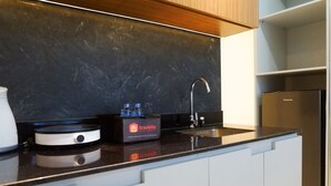 Eine moderne Küche mit schwarzem Arbeitsplatz, einer integrierten Spüle, einer travelio Box und einem Panasonic Kühlschrank.