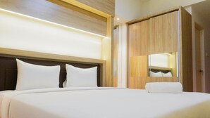 Een hotelkamer met een groot bed, een houten hoofdbord en een houten garderobe met spiegel.