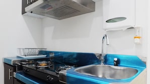 Een keuken met een blauw aanrecht, een roestvrijstalen spoelbak en een gasfornuis.