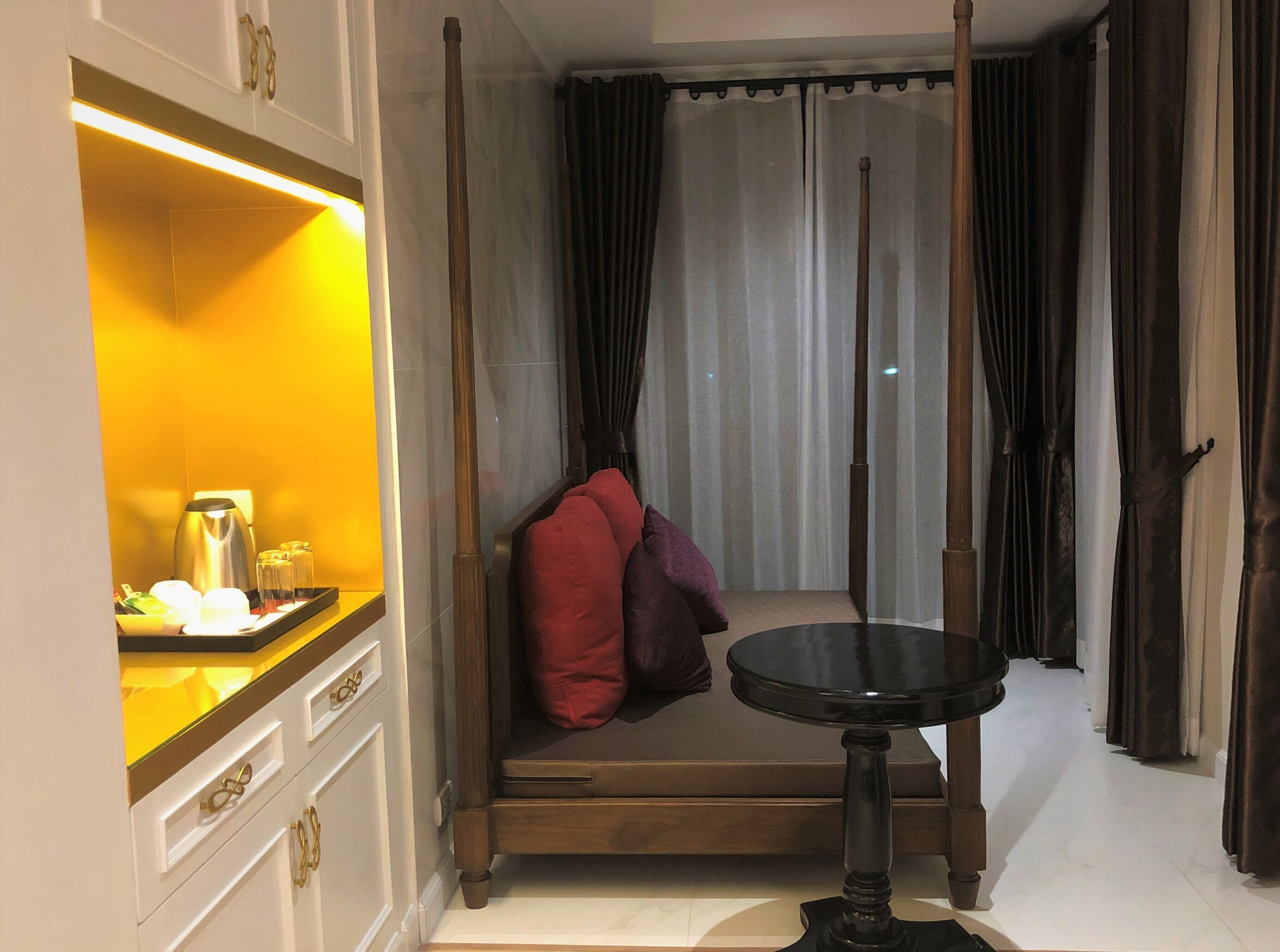 A room with a bed, a bedside table, a lamp, and curtains.