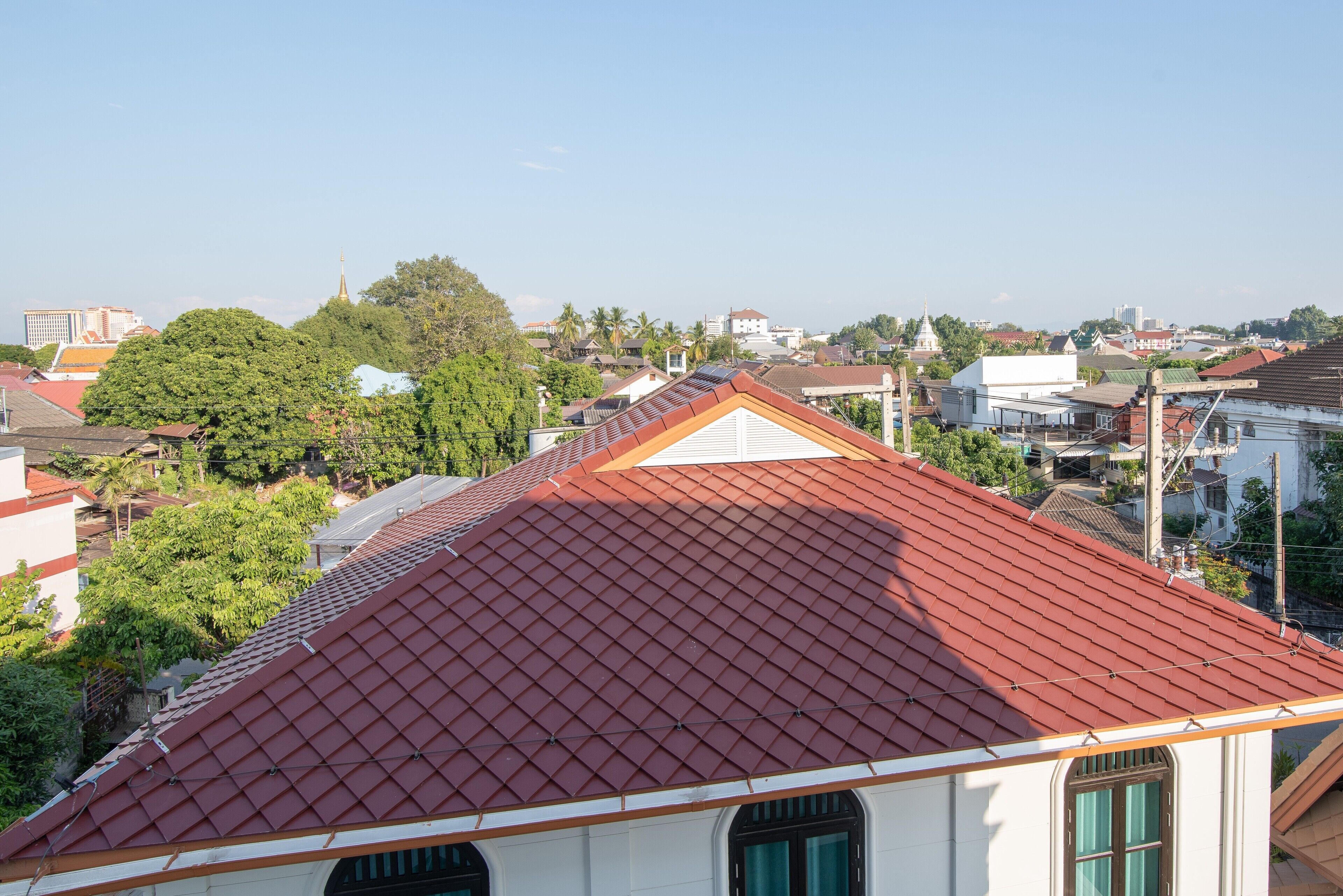 Un edificio con techo de tejas rojas, paredes blancas y contraventanas verdes.