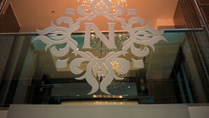 The exterior of NANTA GLAM CM HOTEL & RESIDENCES with a prominent chandelier and a decorative emblem above the entrance.