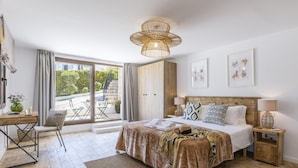 A modern bedroom with a large bed, a desk, and a view of the outdoors. - Villa Pakatoa (Javea / Xàbia)