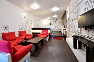 A hotel room with a sofa set, a wooden table, a TV, and a wall with decorative drawings.