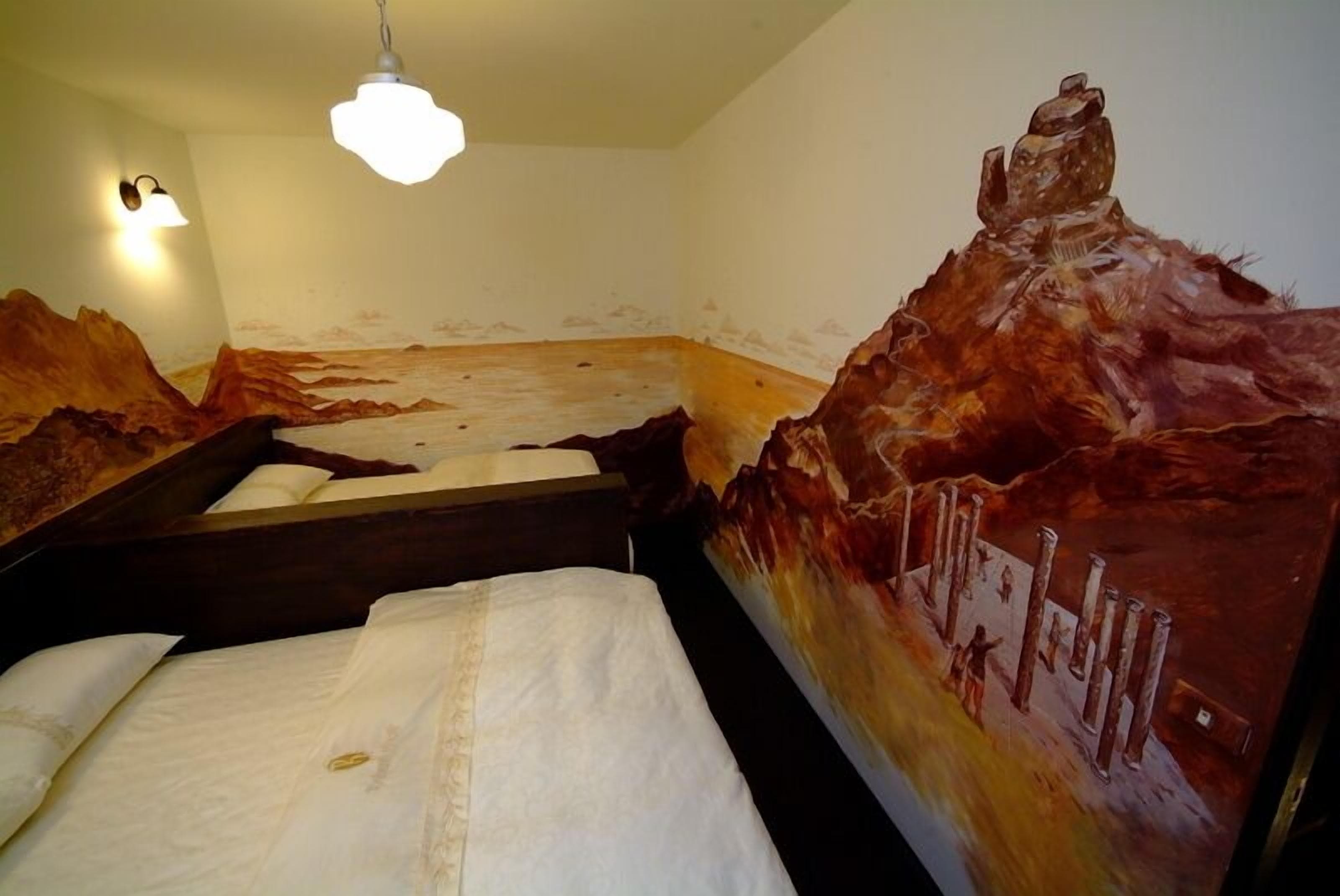Una camera da letto con un letto, un comodino e un murale raffigurante un paesaggio montano.