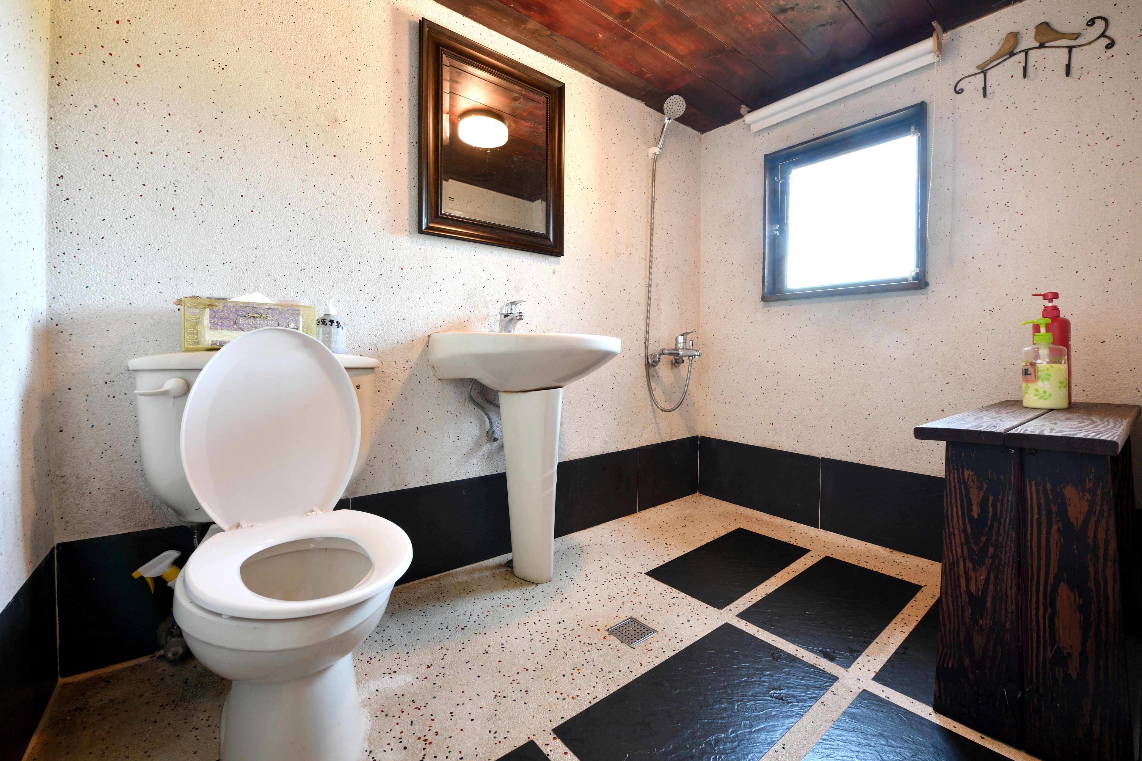 A bathroom with a toilet, sink, shower, and a window.