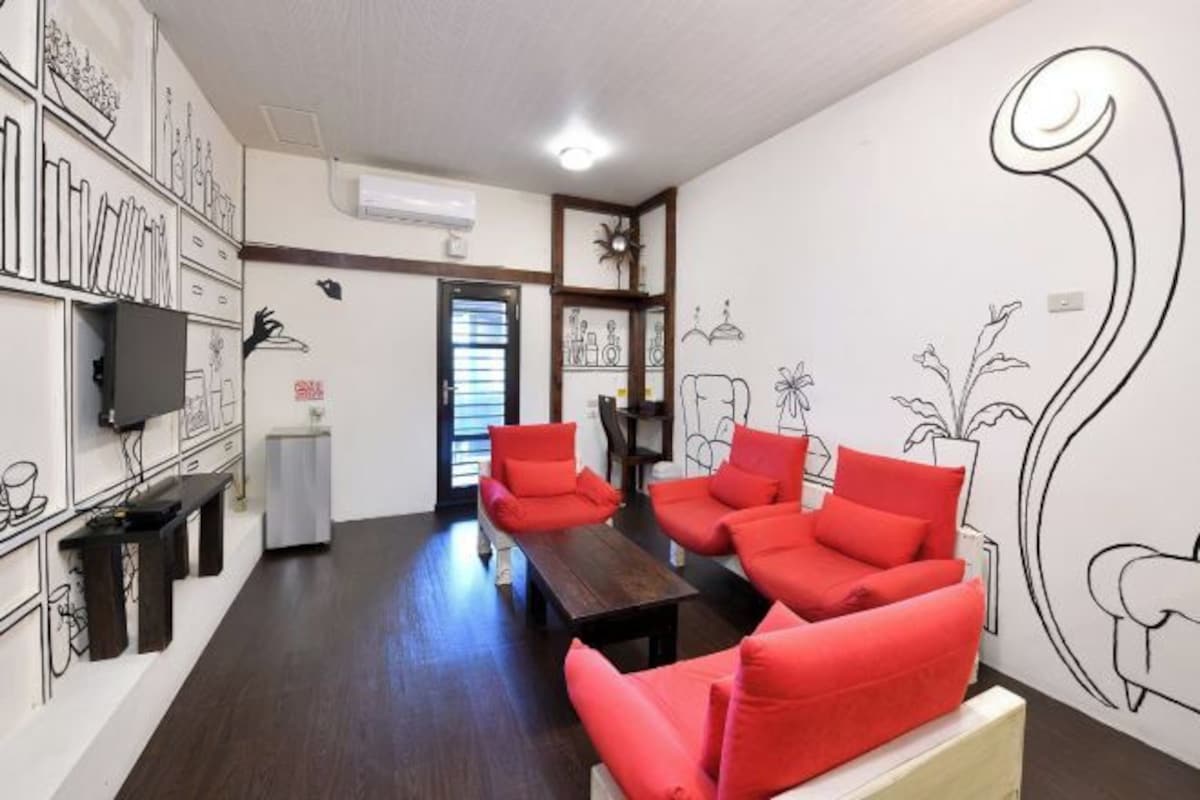 A modern living room with red sofas, a wooden coffee table, and a TV mounted on the wall.