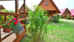 Una cabaña de madera con un porche, rodeada de un jardín cuidado con diversas plantas y flores.