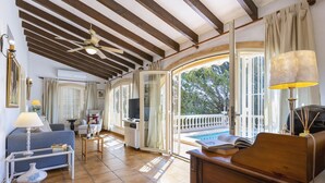 A spacious living area with a pool, wooden ceiling beams, and a view of the outdoors. - Villa Levante (Javea / Xàbia)