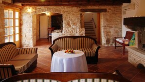 A rustic room with stone walls, a fireplace, and a dining area with striped sofas and a table with fruit. - Marvelous Istrian Villa Morus (Svetvincenat)