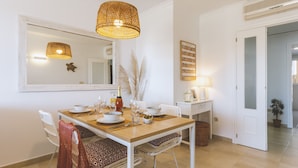 A dining area with a wooden table, white chairs, and a hanging woven light fixture. - Golden Beach (Javea / Xàbia)
