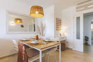 Ein Essbereich mit einem Holztisch, weißen Stühlen und einer hängenden Lampenschirm aus Bändern.