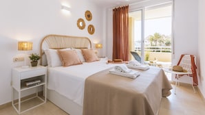 A hotel room with a bed, bedside tables, a chair, a balcony with a view, and a window with curtains. - Golden Beach (Javea / Xàbia)