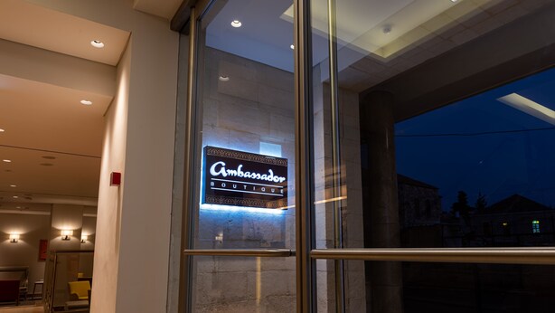 A modern hotel entrance with a glass door and a neon sign for 'Ambassador Boutique'. - Ambassador Boutique Hotel (Jerusalem)