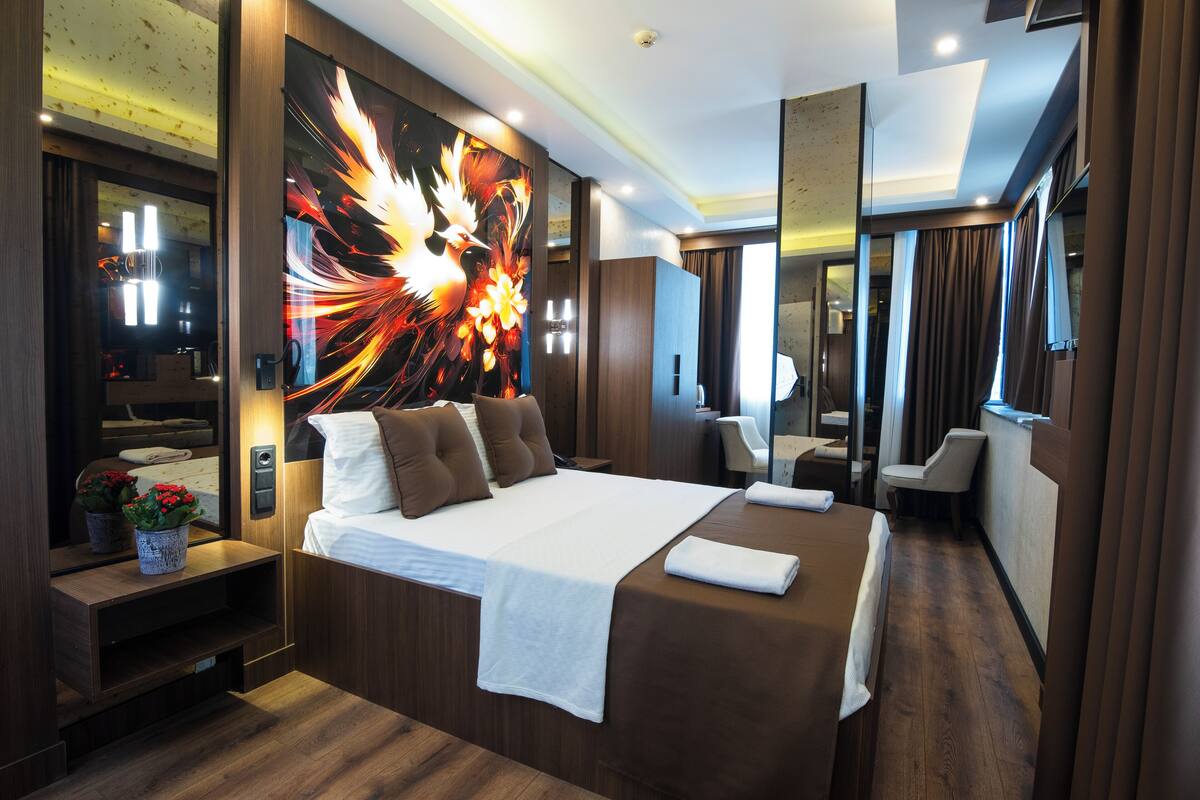 A modern hotel room with a large bed, a wall-mounted TV, and a mirror.