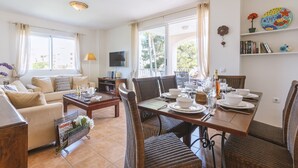 Ein helles Wohnzimmer mit Essbereich, ausgestattet mit einer Couch, einem Couchtisch und einem Esstisch, gedeckt für vier Personen.