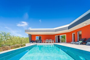 A modern house with a swimming pool, outdoor seating, and a bright orange facade. - Modern Villa With Pool and Terrace (Marcana)