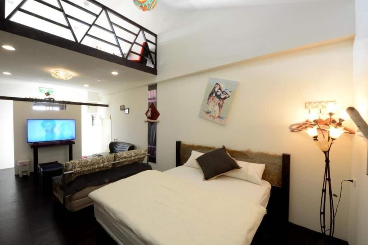 A modern hotel room with a large bed, a television, a sofa, and a decorative lamp.
