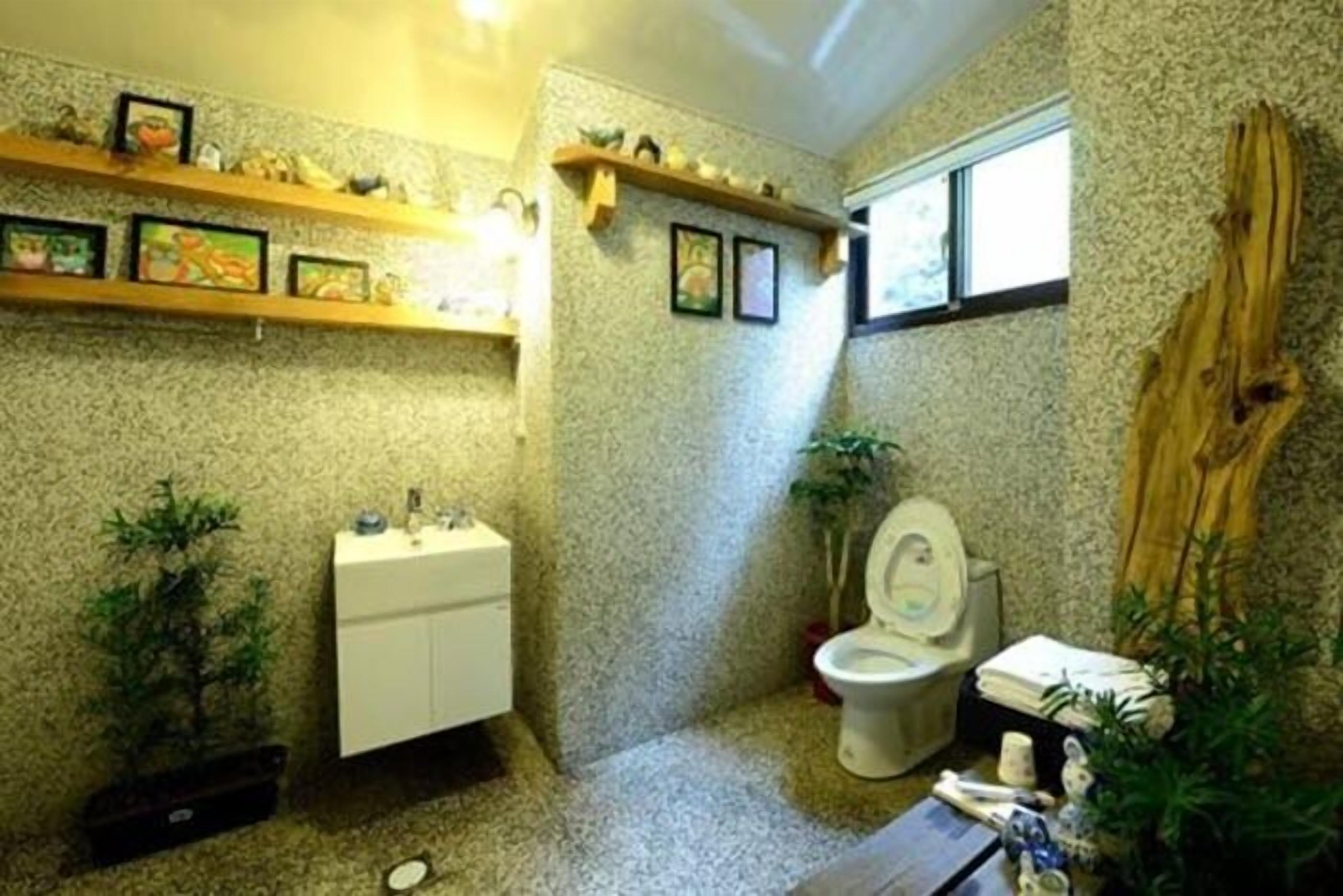 A compact bathroom with a toilet, sink, and shelves with decorative items.