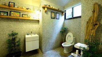 A compact bathroom with a toilet, sink, and shelves with decorative items.