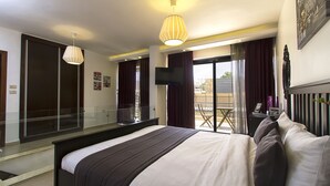 Una habitación de hotel con una cama grande, televisión, balcón con vistas y puerta corredera.