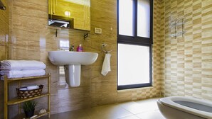 Un baño con lavamanos, inodoro, toallero, repisa con artículos de aseo y ventana.