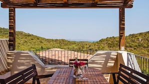 A wooden table with benches on a terrace overlooking a hilly landscape. - Apartment in Golfo Aranci with elevator (Baja Sardinia (SS))