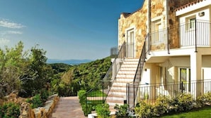 A two-story stone building with a balcony, a staircase, and a pathway leading to the entrance. - Apartment in Golfo Aranci with elevator (Baja Sardinia (SS))