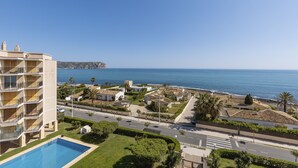 Un hotel costero con piscina, una calle con paso de peatones y vistas al mar y acantilados.