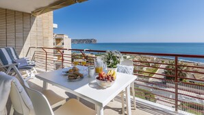 Un balcón con una mesa lista para el desayuno, con vistas a la costa.