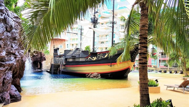 A ship-shaped pool with a waterfall, palm trees, and lounge chairs. - Grande Caribbean Resort - Sleeps 2 (Pattaya)