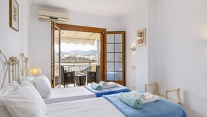 Camera d'albergo con due letti, un balcone con tavolo e sedie, e vista sulla città.