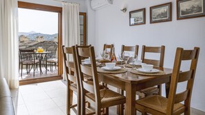 Zona pranzo con tavolo in legno apparecchiato per sei persone, sei sedie in legno e vista sugli edifici attraverso una porta vetrata.