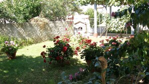 A garden with various potted plants and flowers, a grassy area, and a building in the background. - Apartments Violeta (Liznjan)