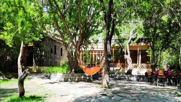 A courtyard with stone flooring, a hammock, and outdoor seating. - Nubra Organic Retreat - Hunder - Campsite (Leh)