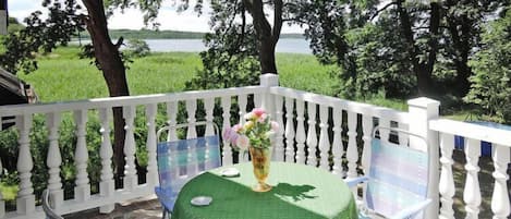 A balcony with a table, chairs, and a vase of flowers.