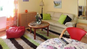 A living room with a sofa, a red bean bag, a round coffee table with a vase, a lamp, and a mirror on the wall. - New holiday home in Nowe Warpno for 6 persons (Nowe Warpno)