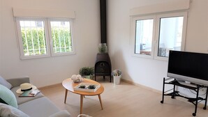 Una sala de estar con sofá, una mesa de centro, un televisor sobre un mueble bajo y una chimenea.