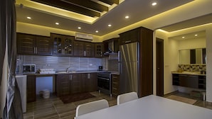 A modern kitchen with dark wooden cabinets, a stainless steel refrigerator, and a dining area with a white table and chairs.