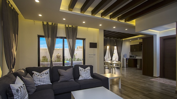 A modern living room with a sectional sofa, a coffee table, and a dining area with a table and chairs.