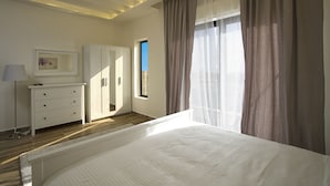 A bedroom with a bed, a dresser, a mirror, and a window with curtains.