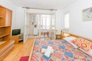Quarto com cama, televisão, escrivaninha e cadeira.