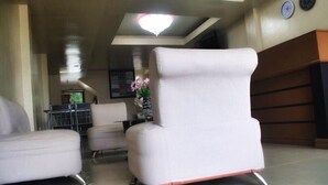 A modern lobby with two white armchairs, a reception desk, and a chandelier. - Mati Budget Inn (Mati)