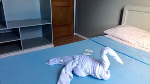 A hotel room with a blue bedspread, a white pillow, and a wooden wardrobe. - Mati Budget Inn (Mati)