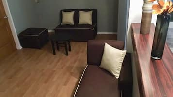A living room with a dark brown sofa, a wooden coffee table, and a small table with a vase of flowers.