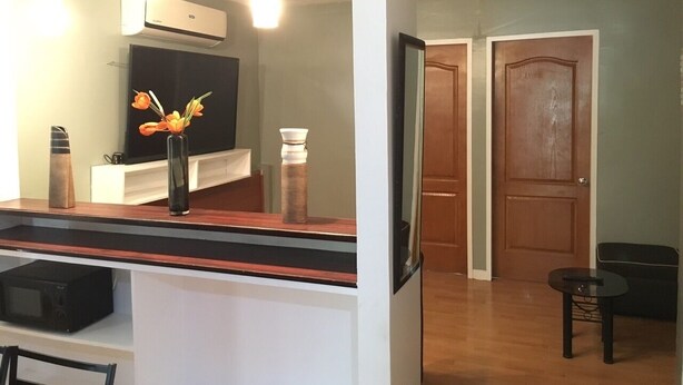 A modern kitchen with a flat-screen TV, a wooden countertop, and a vase with flowers. - Mati Budget Inn (Mati)