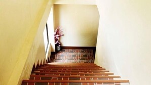 A staircase with a brick-patterned floor and wooden handrails. - Mati Budget Inn (Mati)