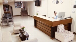 A reception area with a reception desk, a computer, a television, and a seating area with chairs and a sofa. - Mati Budget Inn (Mati)